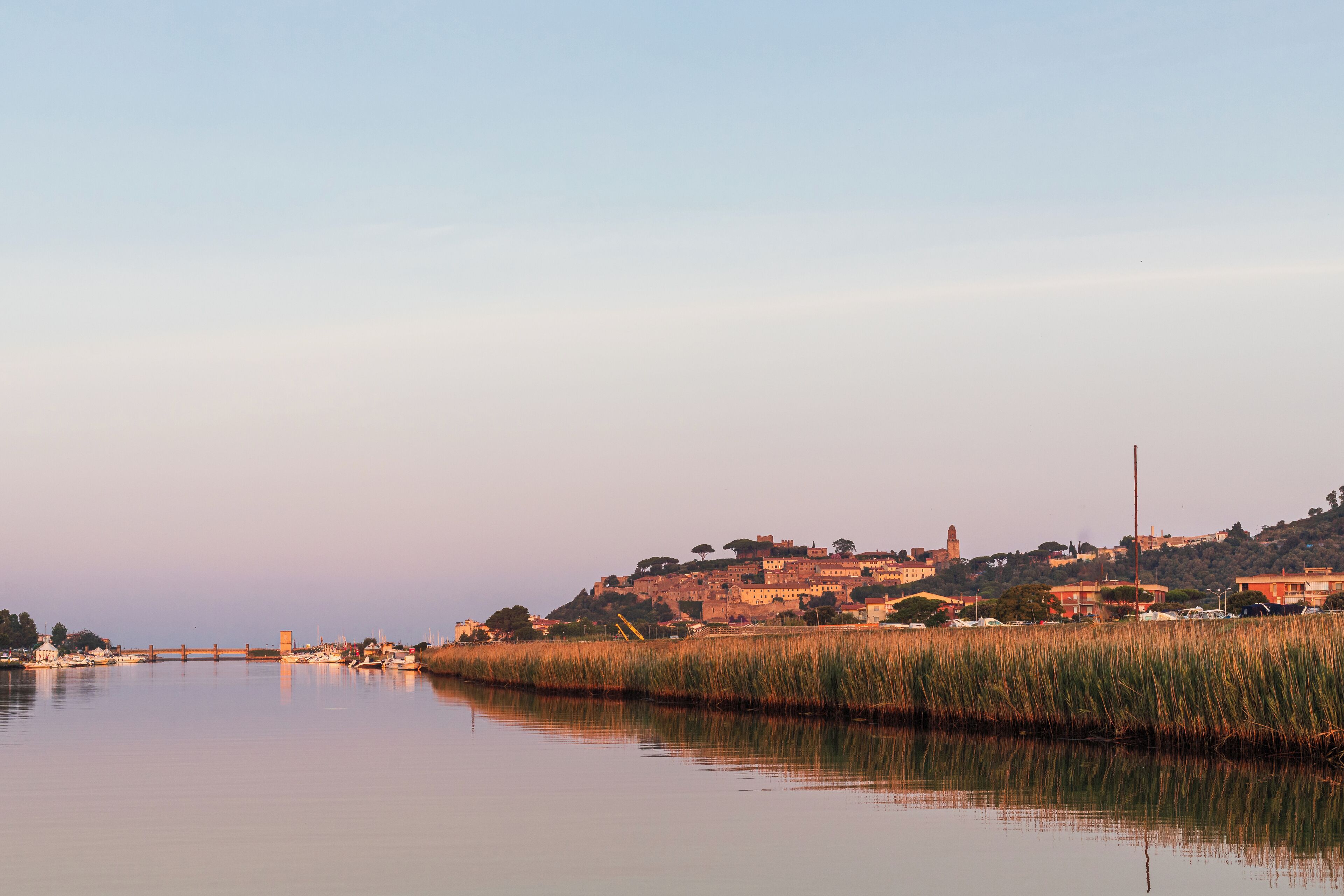 Une vue sur une ville historique, avec ses bâtiments perchés sur une colline, un pont et une tour, le tout surplombant une rivière.