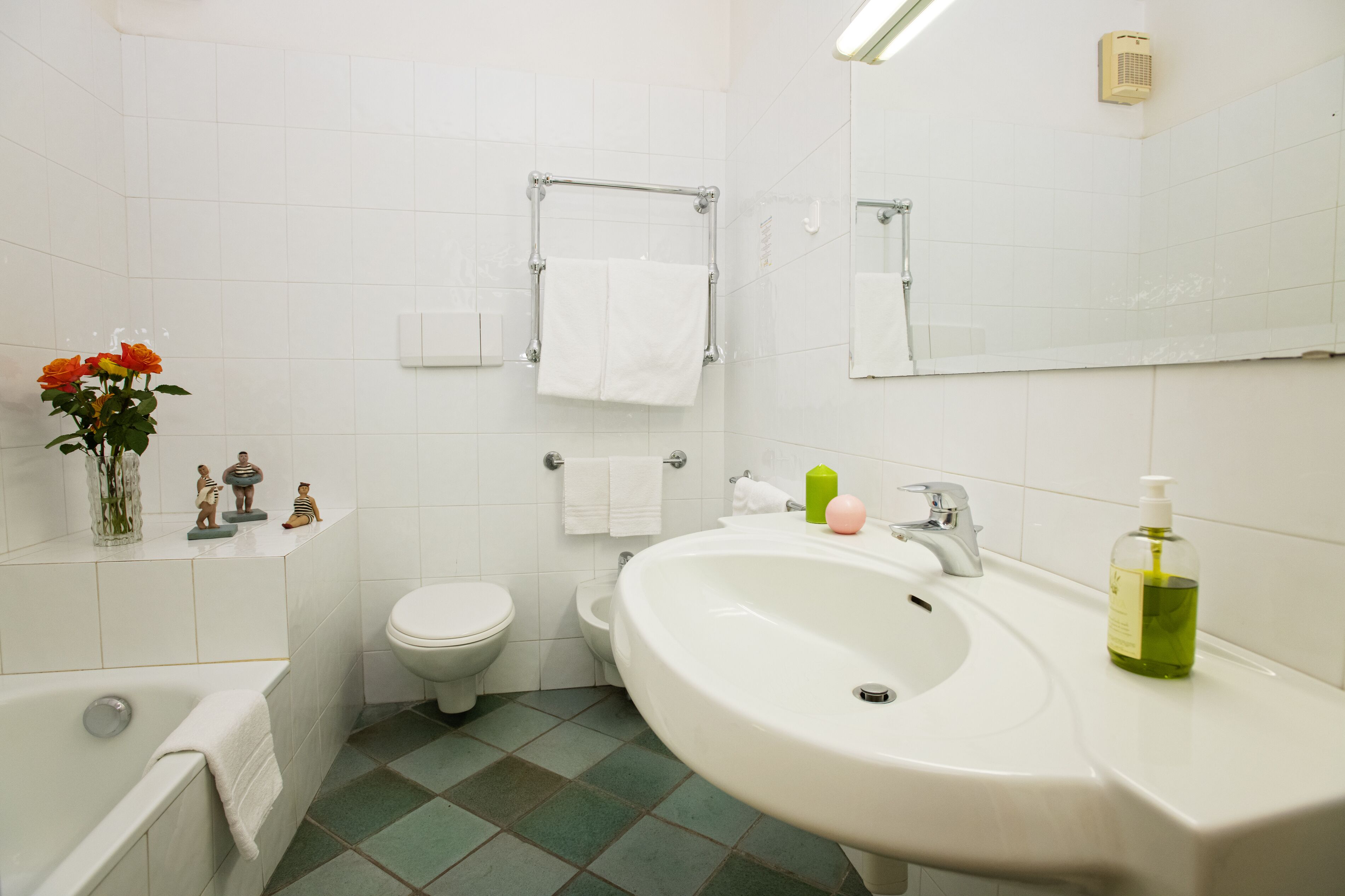 A bathroom with a bathtub, toilet, sink, and a mirror.