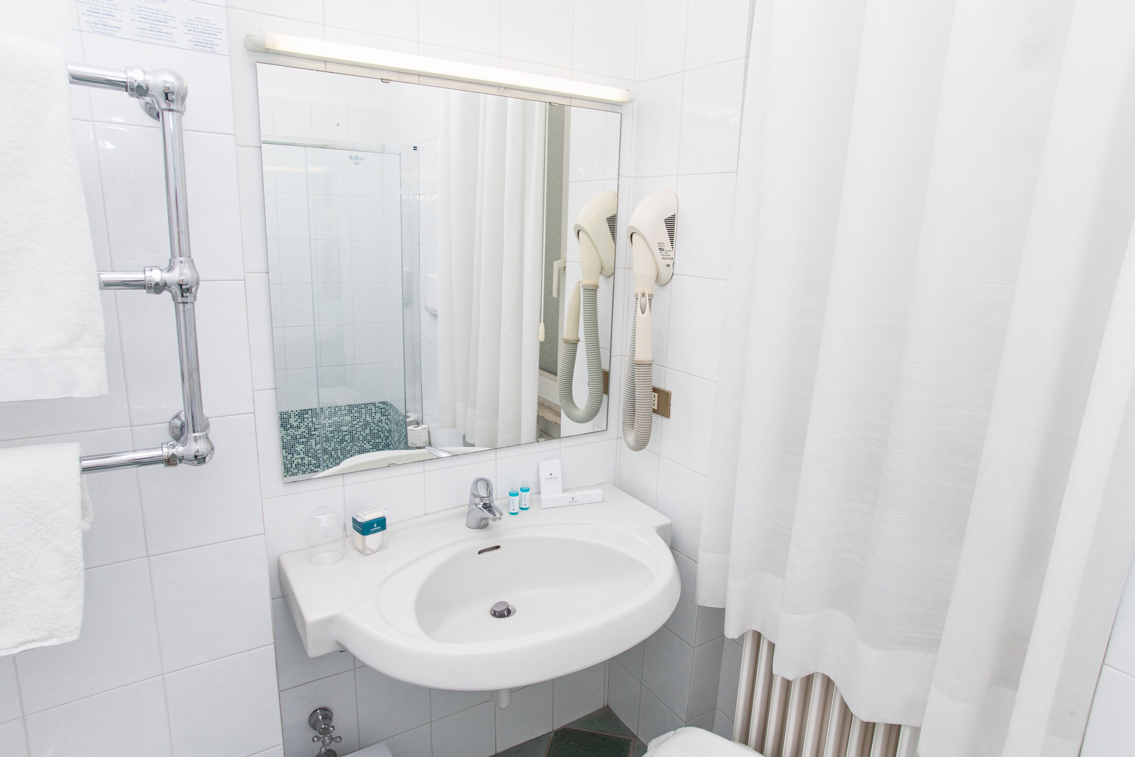 Une salle de bain avec un lavabo blanc, un miroir et un porte-serviettes.