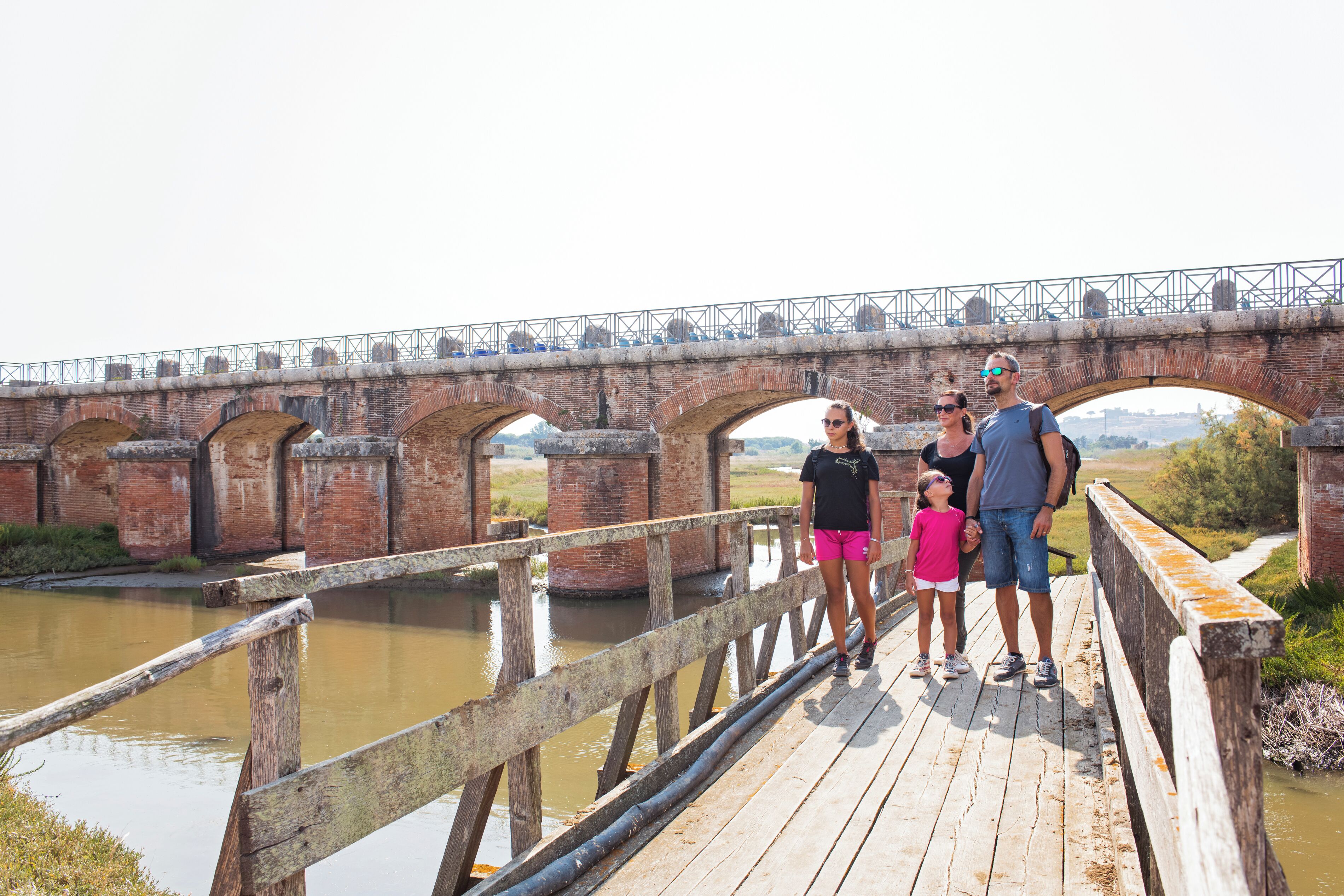 Uma família em uma ponte de madeira sobre um rio.