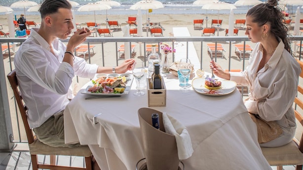 Ein Paar speist an einem Tisch mit Blick auf Strand und Meer.