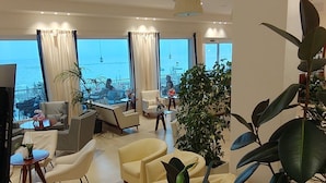 Ein geräumiges Wohnzimmer mit großem Fernseher, bequemen Sitzmöglichkeiten und Blick aufs Meer.