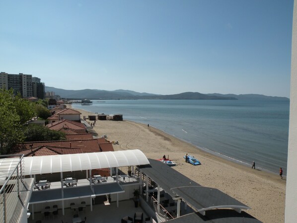 Un hôtel situé sur la côte, doté d’une terrasse et offrant une vue sur la plage et la mer.