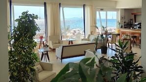 Ein großzügiger Wohnbereich mit einem großen Fenster und Meerblick, ein Essbereich und eine Küche.