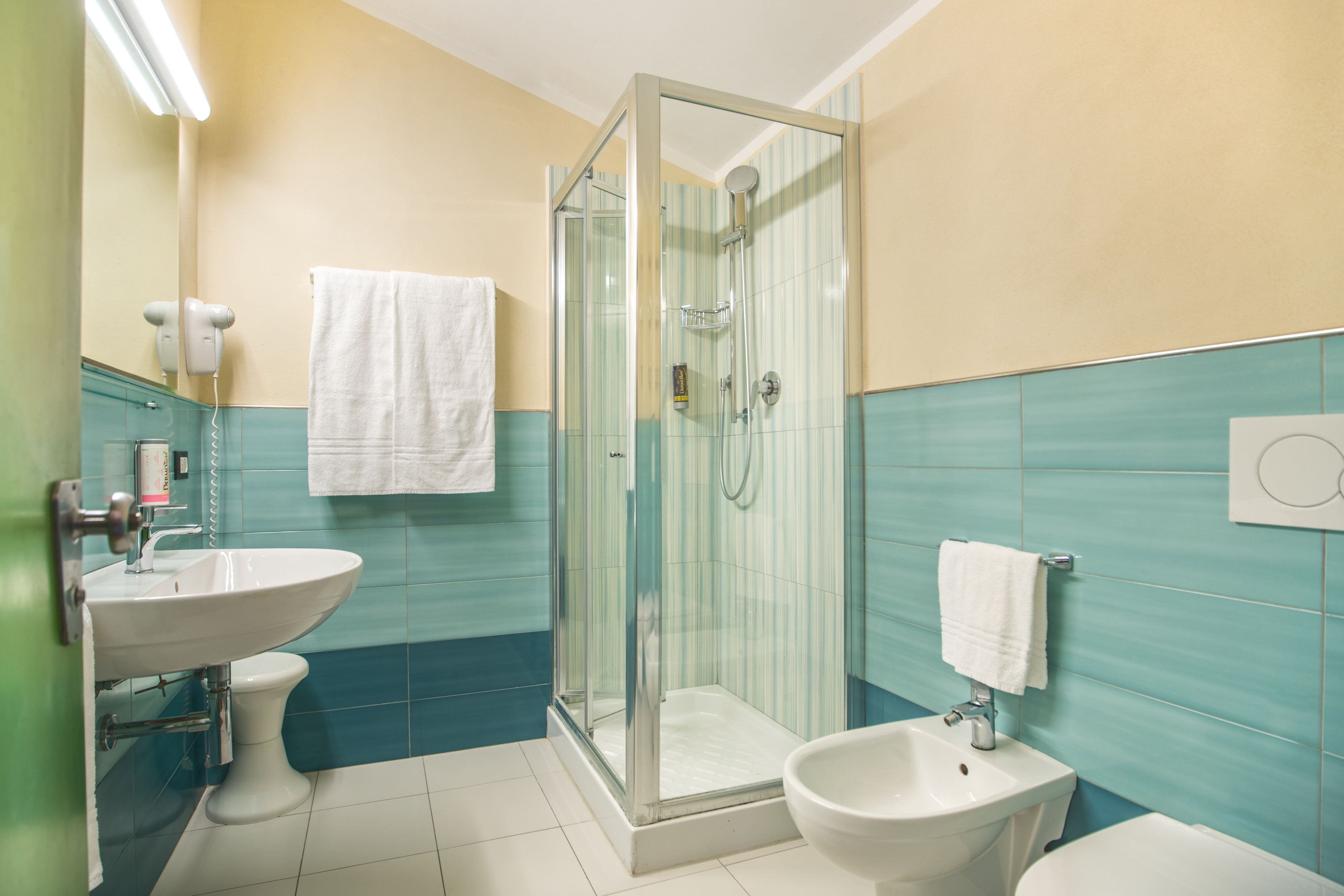 A bathroom with a glass-enclosed shower, a sink, a bidet, and a toilet.