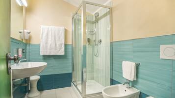 Un baño con ducha de vidrio, lavamanos, lavabo y retrete.