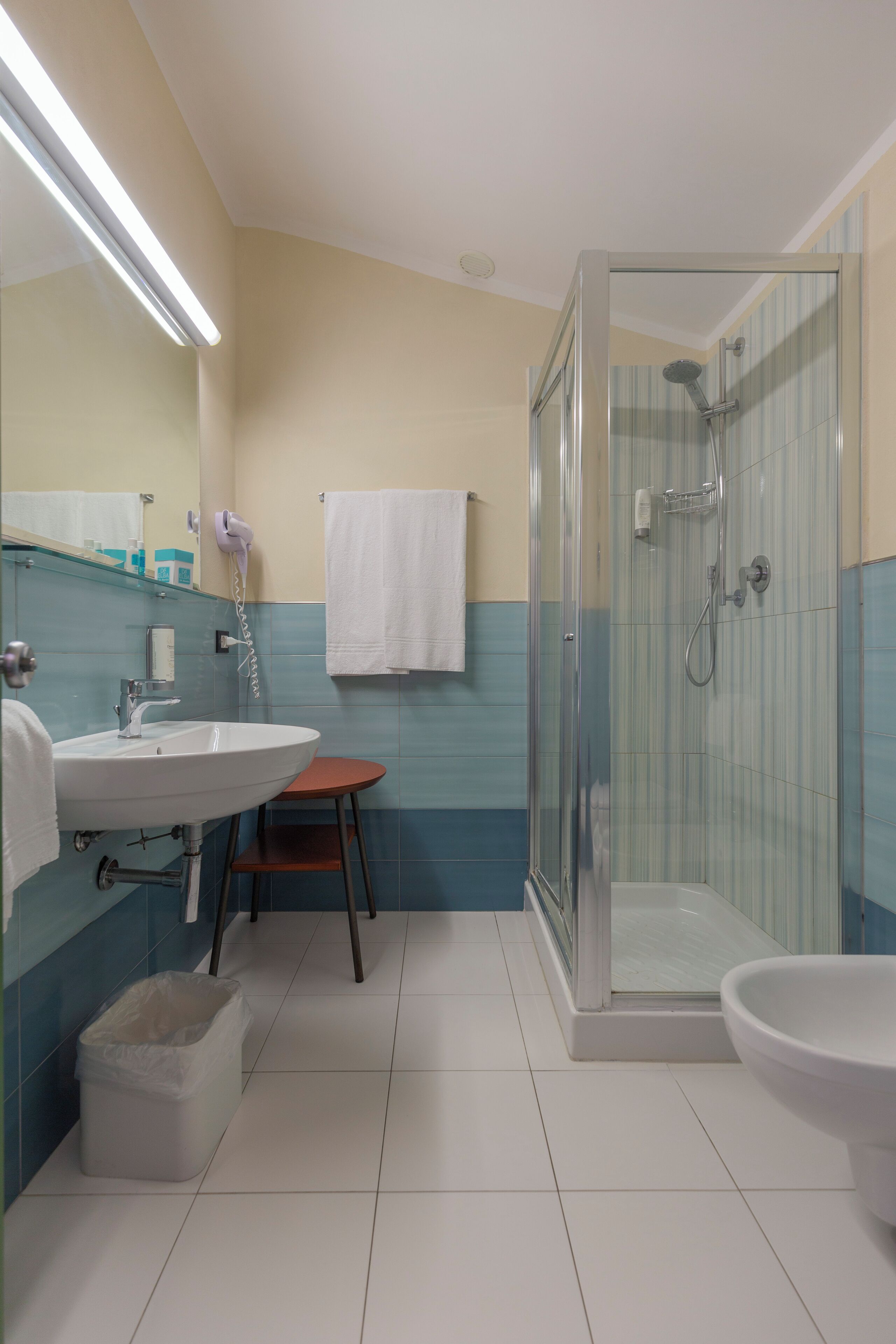 A bathroom with a glass-enclosed shower, a sink, and a bidet.