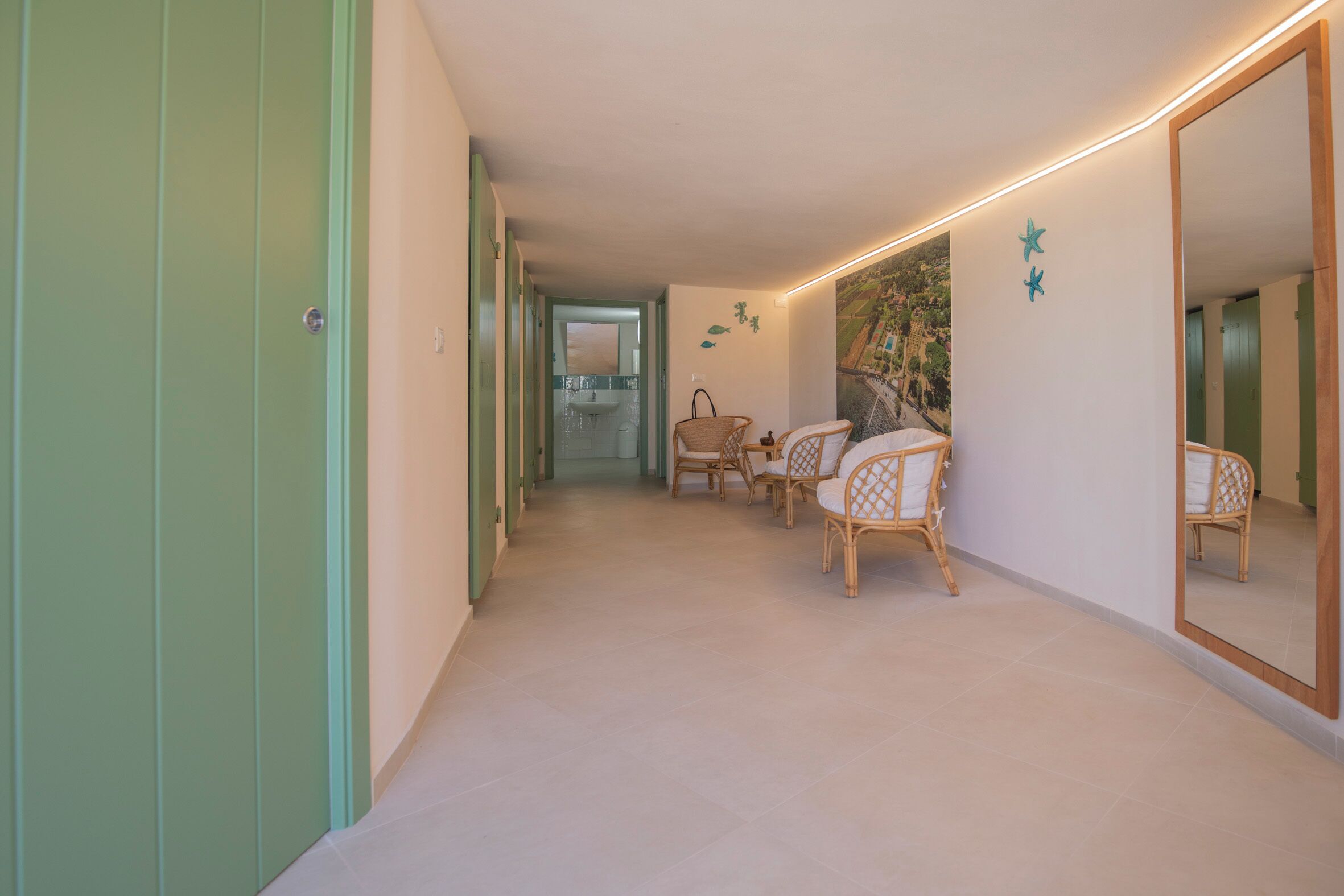 A hallway with a green door, wicker chairs, a large mirror, and a wall with star decorations.