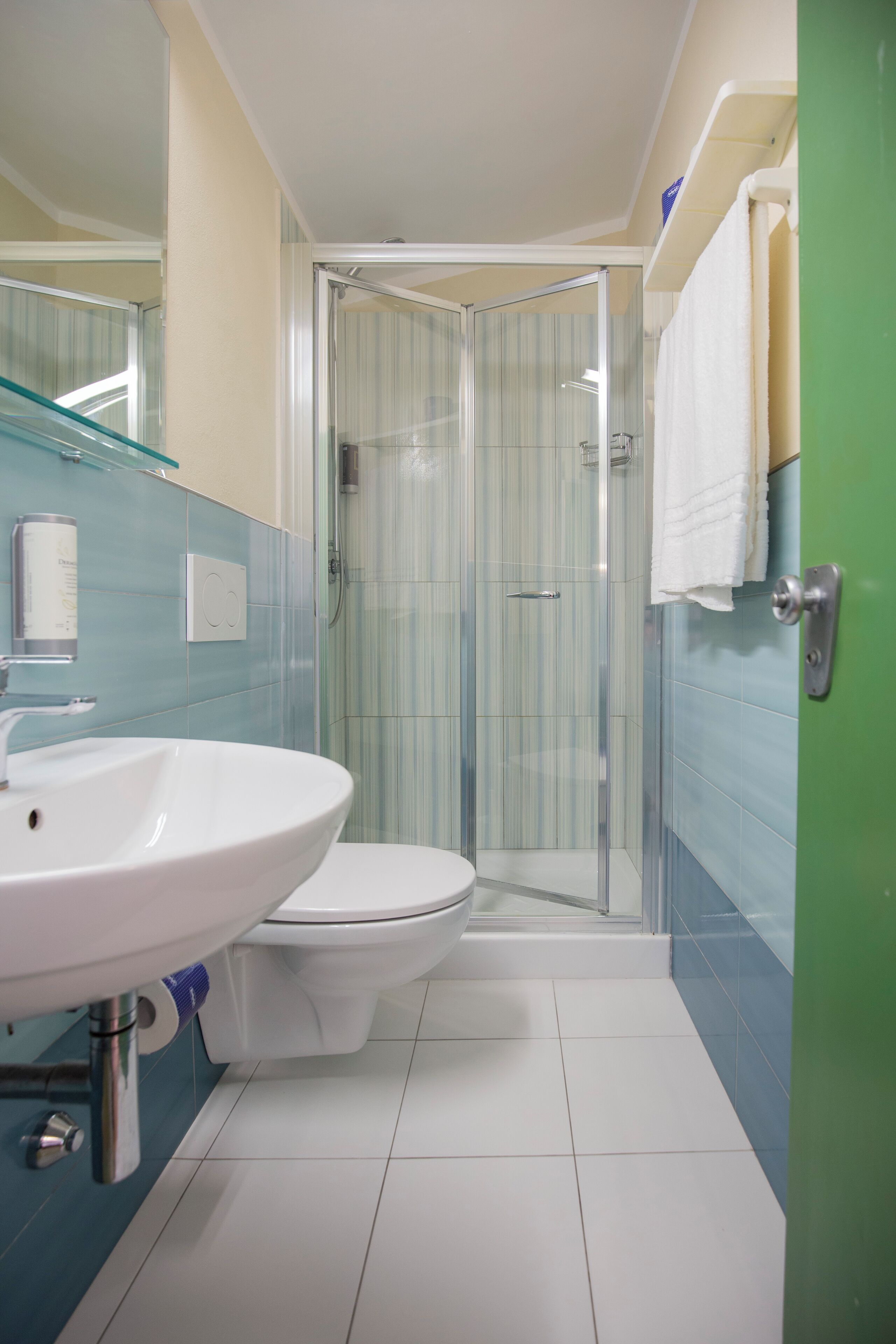Ein Badezimmer mit einer Duschkabine aus Glas, einem weißen Waschbecken und einer Toilette.