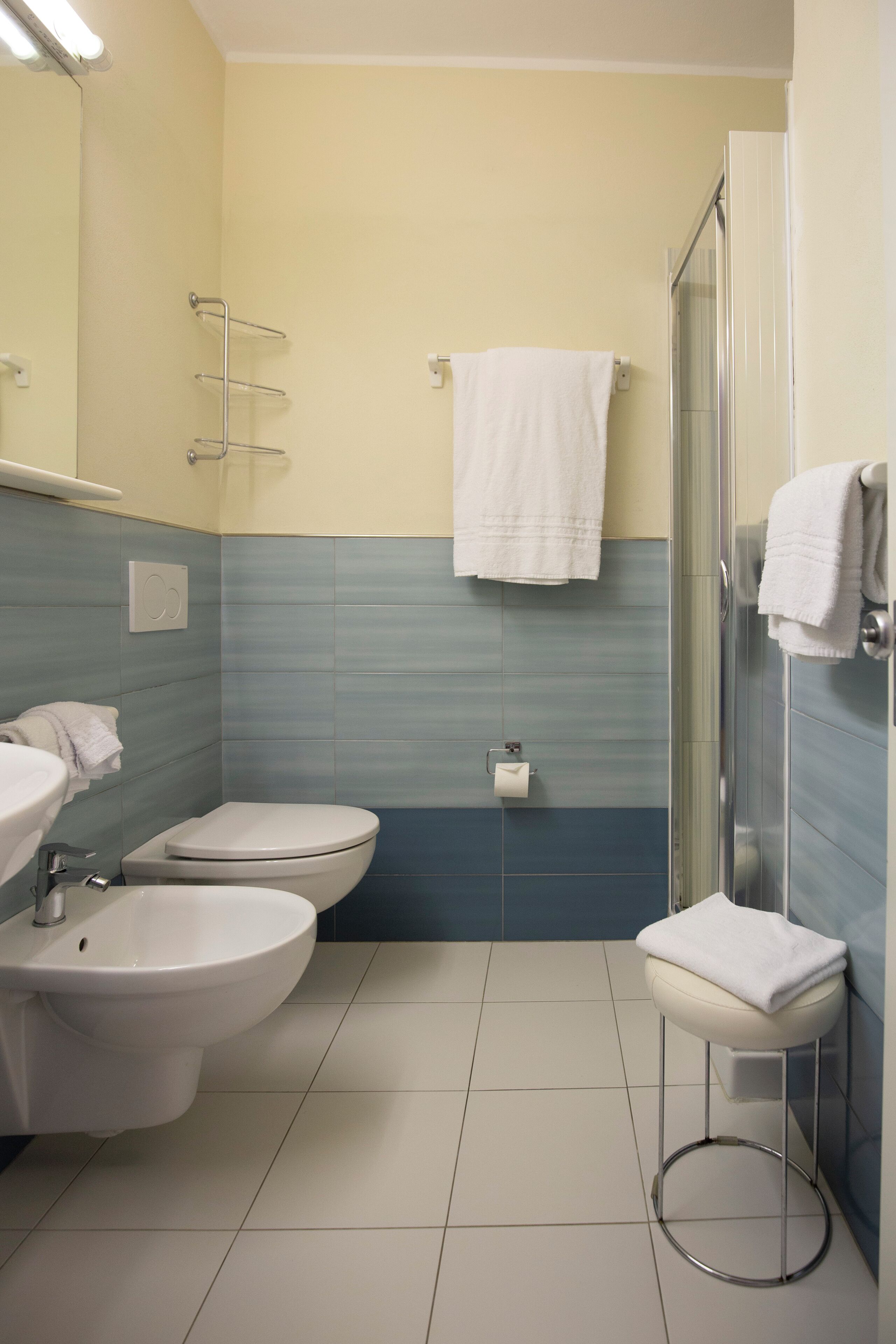 A bathroom with a toilet, bidet, sink, and a glass shower stall.