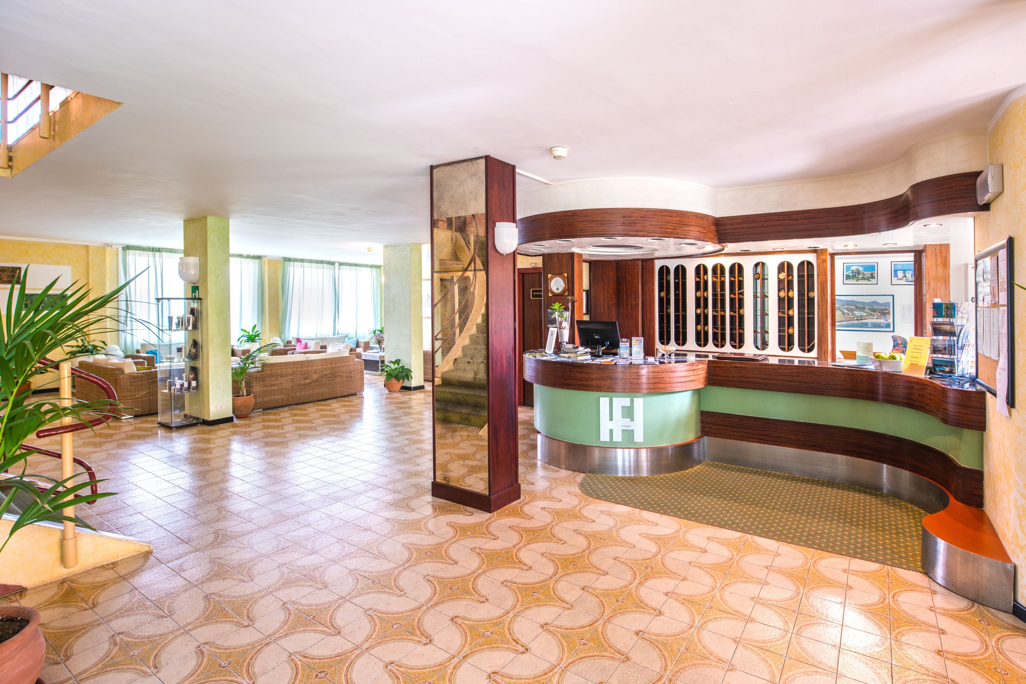 Una hall d'hotel con reception, area salotto e una scalinata.