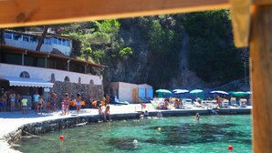 A pool area with people swimming and sunbathing, surrounded by buildings and greenery. - JR Resort Elba International (Capoliveri)
