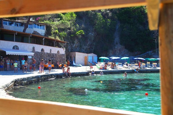 A pool area with people swimming and sunbathing, surrounded by buildings and greenery. - JR Resort Elba International (Capoliveri)