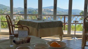 A dining table with breakfast items, a view of mountains and water, and a sign indicating a restaurant. - JR Resort Elba International (Capoliveri)