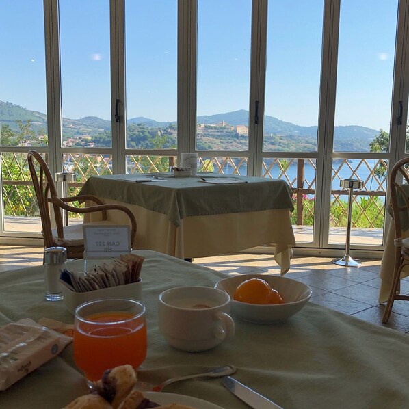 A dining table with breakfast items, a view of mountains and water, and a sign indicating a restaurant. - JR Resort Elba International (Capoliveri)