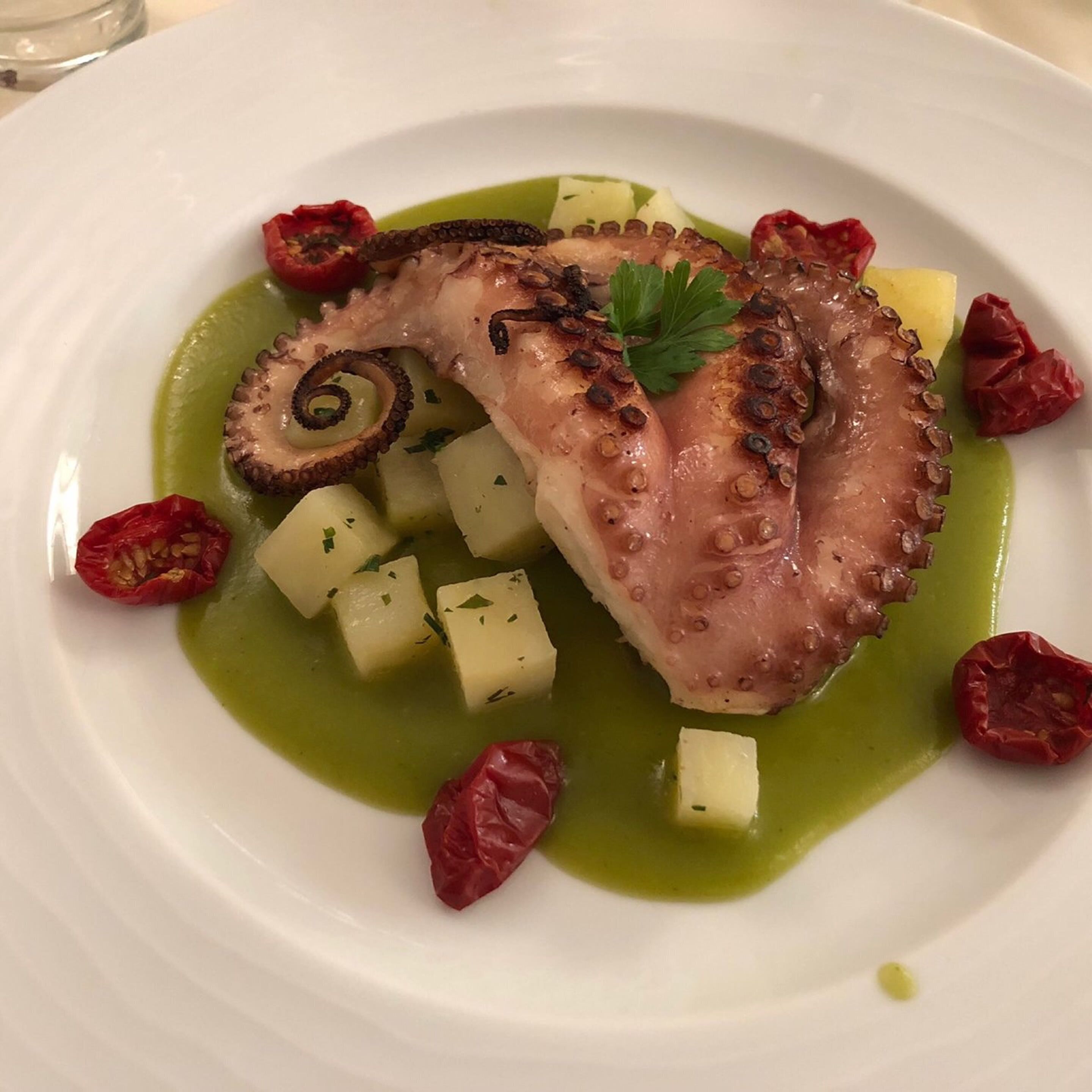 Ein Teller mit Oktopus, Kartoffeln und roten Paprika.