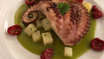 Ein Teller mit Oktopus, Kartoffeln und roten Paprika.