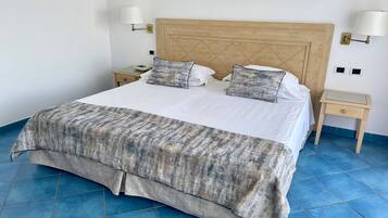 A bed with a wooden headboard, two bedside tables, and a blue-tiled floor.