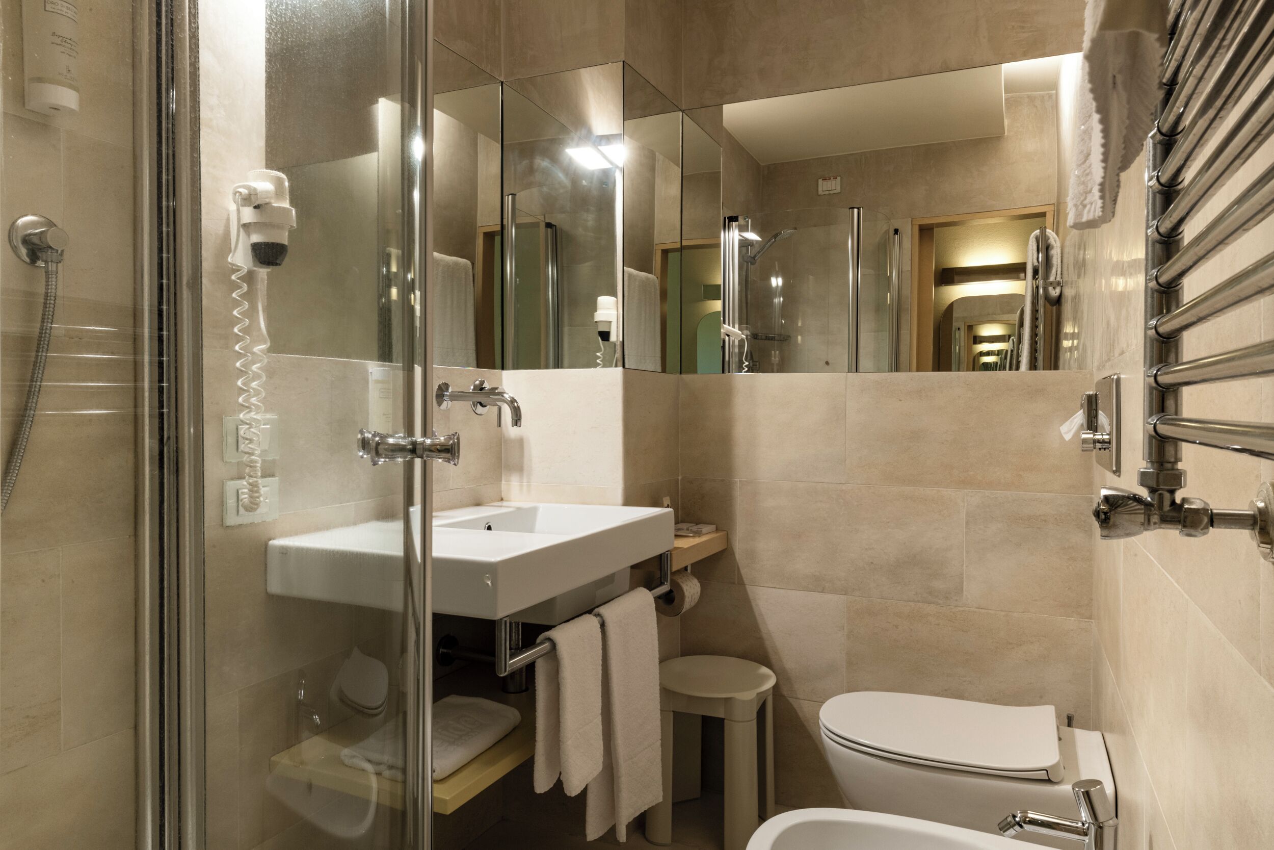 A modern bathroom with a glass-enclosed shower, a sink, a toilet, and a mirror.