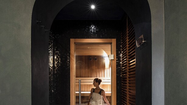 A hallway leading to a room with a wooden bench and a tiled wall. - Albergo Celide (Lucca)
