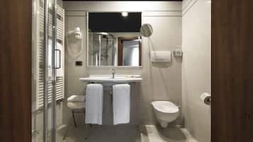 A modern bathroom with a glass shower enclosure, a sink with a mirror above, a toilet, and a bidet.