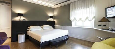 A modern bedroom with a large bed, bedside lamps, a TV, and a window with curtains.