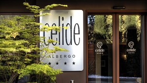 A hotel entrance with a sign reading "celide ALBERGO" and a glass door reflecting the sign. - Albergo Celide (Lucca)