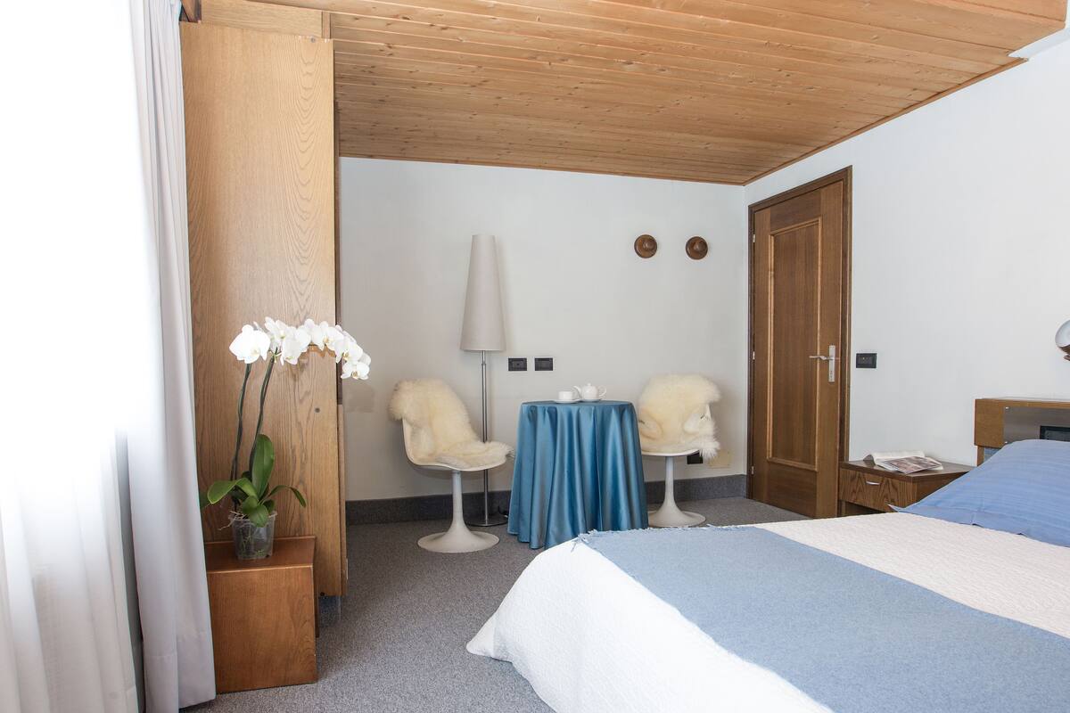 Ein Hotelzimmer mit einem Bett, zwei Stühlen, einem Tisch und einem Holzschrank.