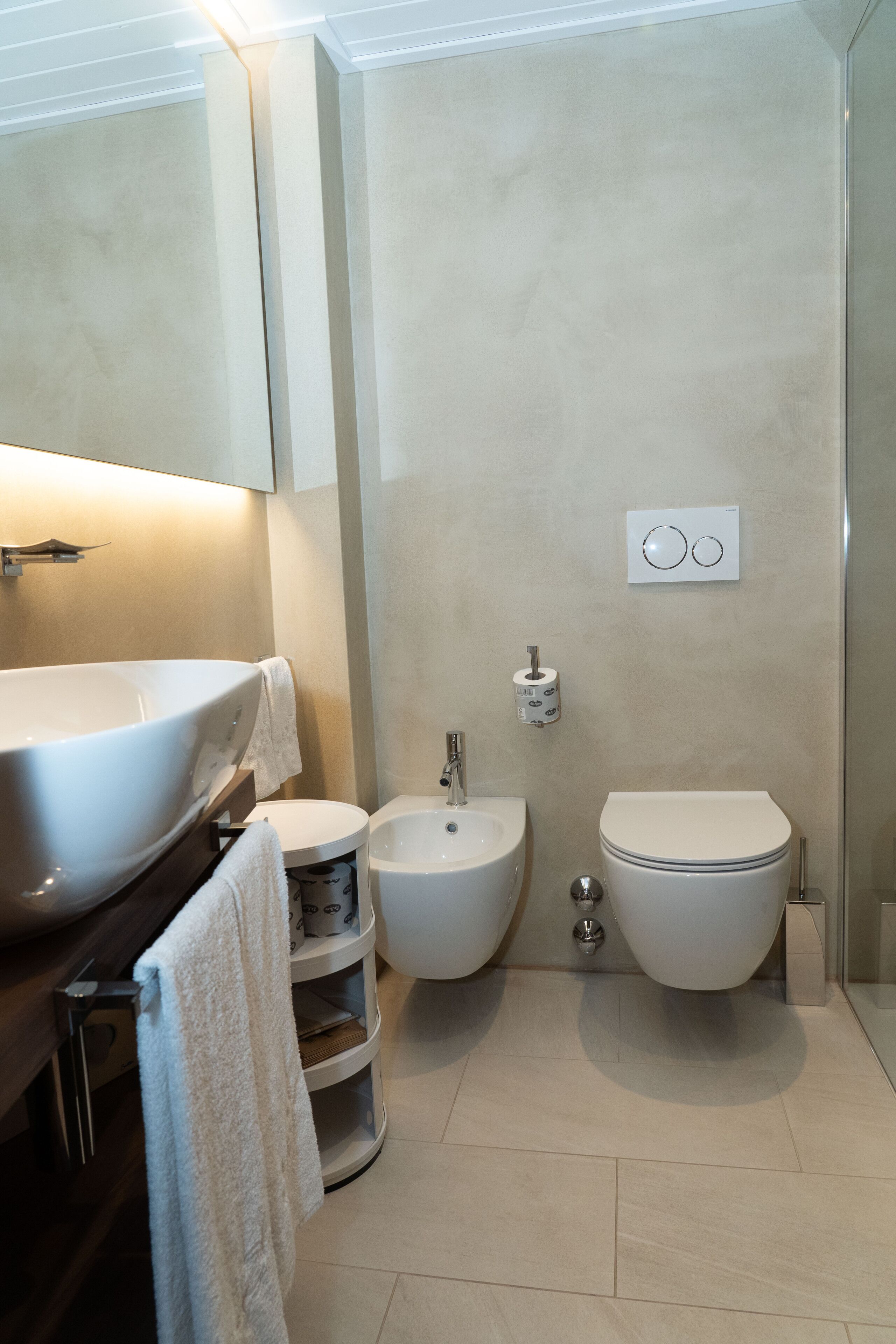 A modern bathroom with a large white sink, a bidet, and a toilet.