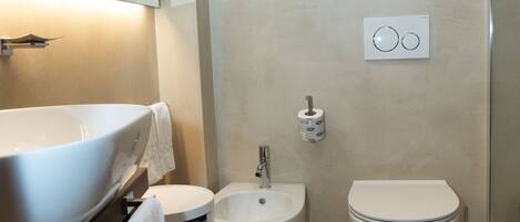 Un baño moderno con un lavamanos grande de color blanco, un bidé y un inodoro.