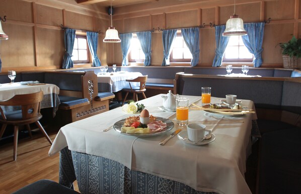 Un ambiente cálido con mesas de madera y cortinas azules, ideal para el desayuno.
