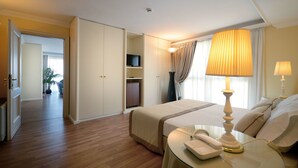 A hotel room with a bed, bedside table with a lamp, a telephone, a television on a shelf, and a wardrobe. - Ambasciatori Palace (Montecatini Terme)