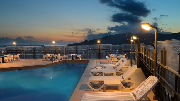 A rooftop pool area with lounge chairs and tables, surrounded by a glass barrier. - Ambasciatori Palace (Montecatini Terme)