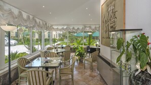 A dining area with glass tables and chairs, a large potted plant, and a framed artwork on the wall. - Hotel Verdemare (Pietrasanta)