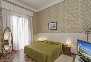 A bedroom with a bed, a television, a mirror, and a nightstand with lamps. - Hotel Verdemare (Pietrasanta)