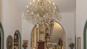 A grand hallway with a chandelier, a red carpet, and a staircase leading to a dining area. - Hotel Verdemare (Pietrasanta)