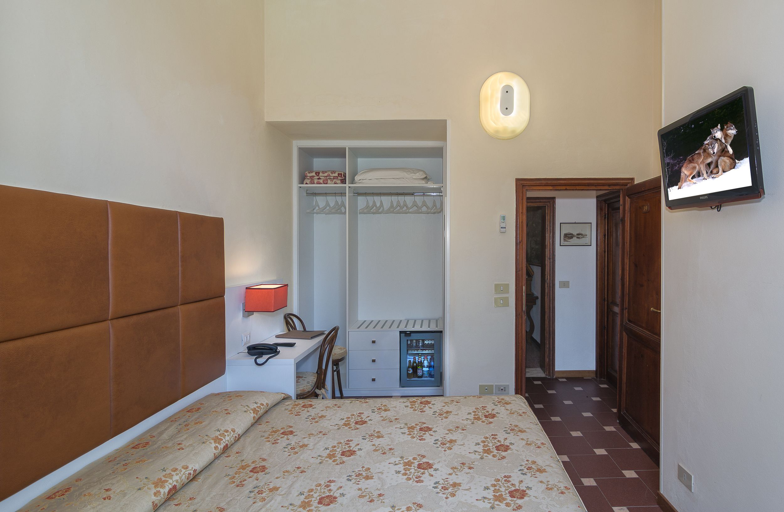 Un dormitorio con cama, escritorio, armario y televisión.