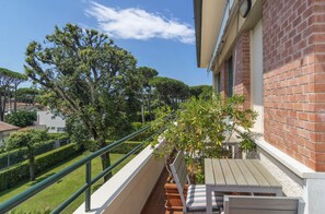 A balcony with a view of a garden, a brick wall, and a wooden table. - Hotel Villa Edera (Camaiore)