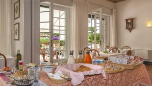 Comedor con una mesa dispuesta para el desayuno, incluyendo pan, bollería y bebidas.