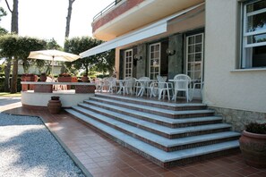 A patio area with outdoor seating, steps leading to a covered entrance, and potted plants. - Hotel Villa Edera (Camaiore)