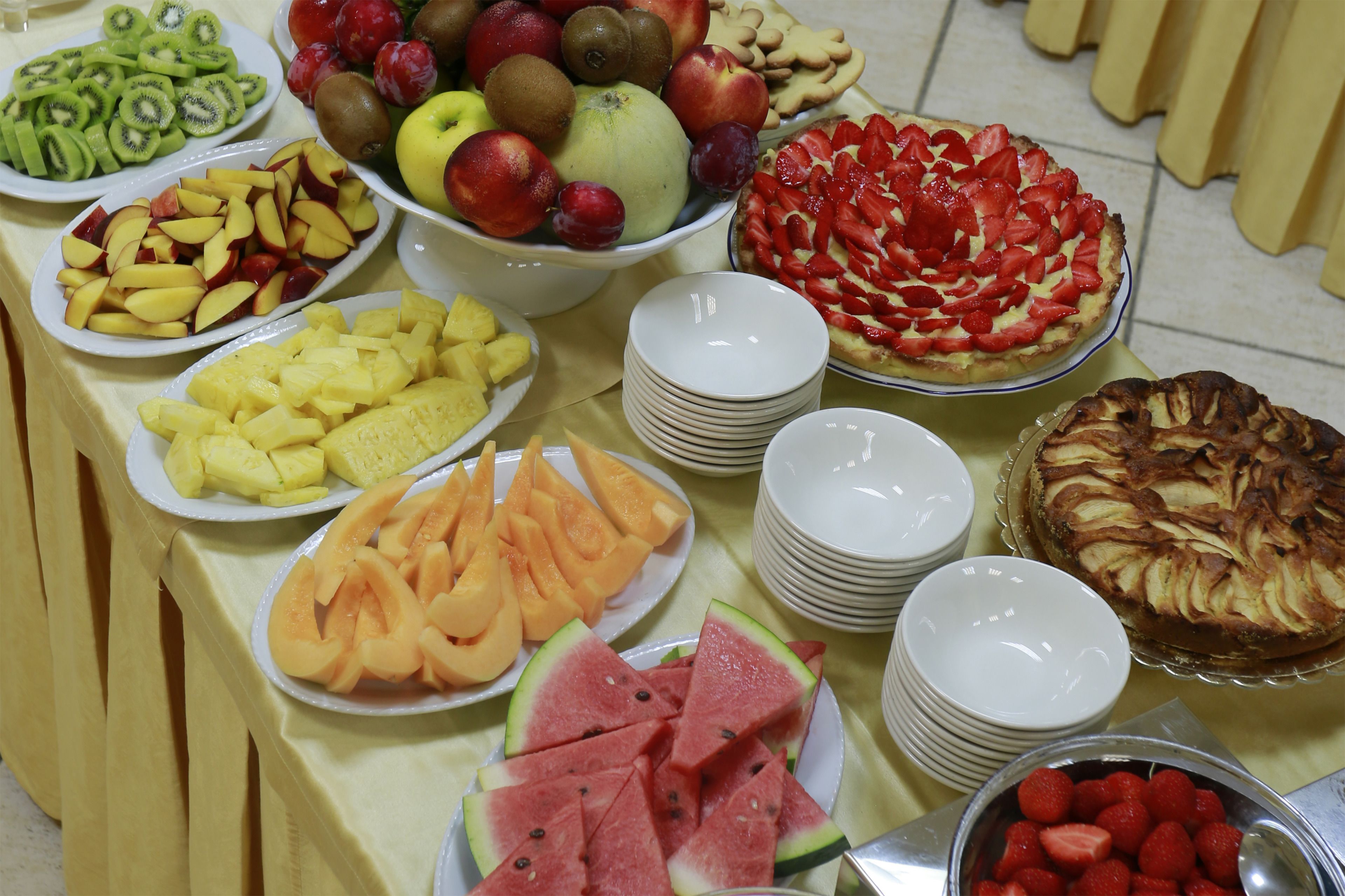 A buffet table with various fruits and desserts.