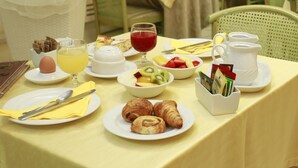 A breakfast table with plates of croissants, fruit, and a jug of juice. - Hotel Katy (Viareggio)