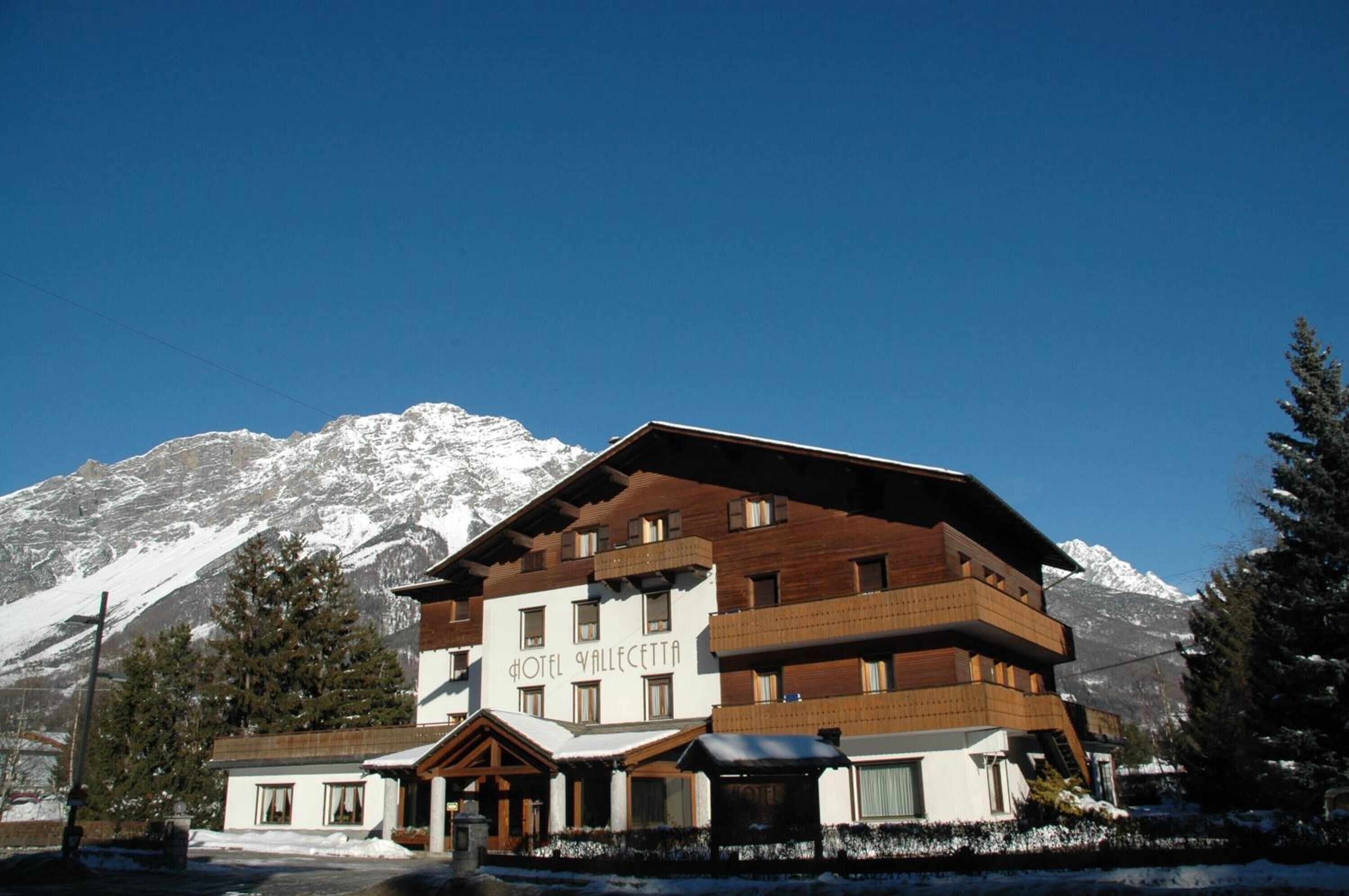 A multi-story hotel with a wooden facade and a sign reading "HOTEL VALLECCITA".