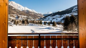 A snowy mountain landscape with a wooden fence in the foreground.