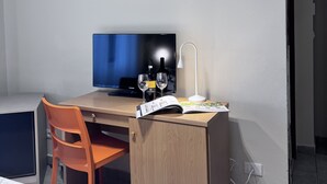 A room with a wooden desk, a computer, two wine glasses, a bottle, and a lamp. - Hotel La Magione (Poggibonsi)