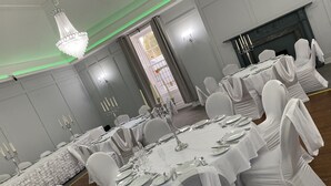A banquet hall with round tables set for dining, white chairs, and chandeliers. - Royal Dunkeld (Dunkeld)
