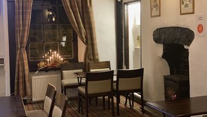 A cozy dining area with a fireplace, plaid curtains, and a table with chairs. - Royal Dunkeld (Dunkeld)