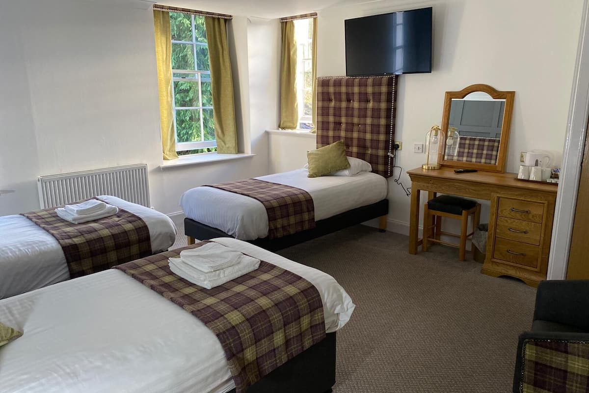 A hotel room with two beds, a desk with a mirror, and a TV mounted on the wall.