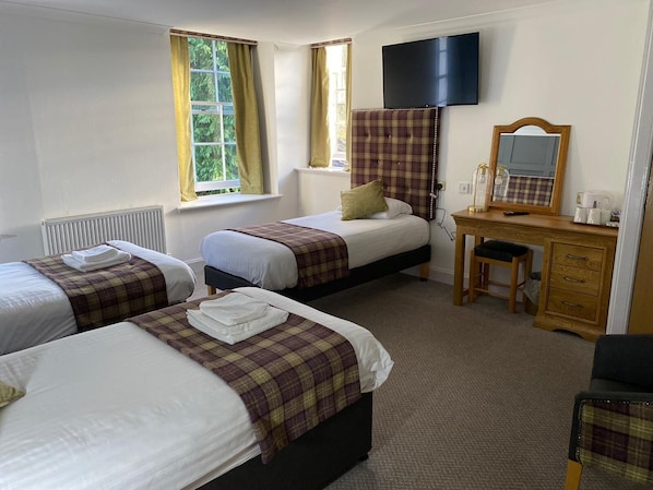 A hotel room with two beds, a desk with a mirror, and a TV mounted on the wall.