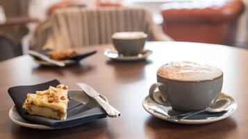 A dining table with a slice of cake, a cup of coffee, and a spoon.